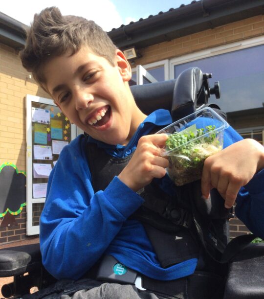 Photo of a boy with a neurodisability in a gardening lesson at Pace school